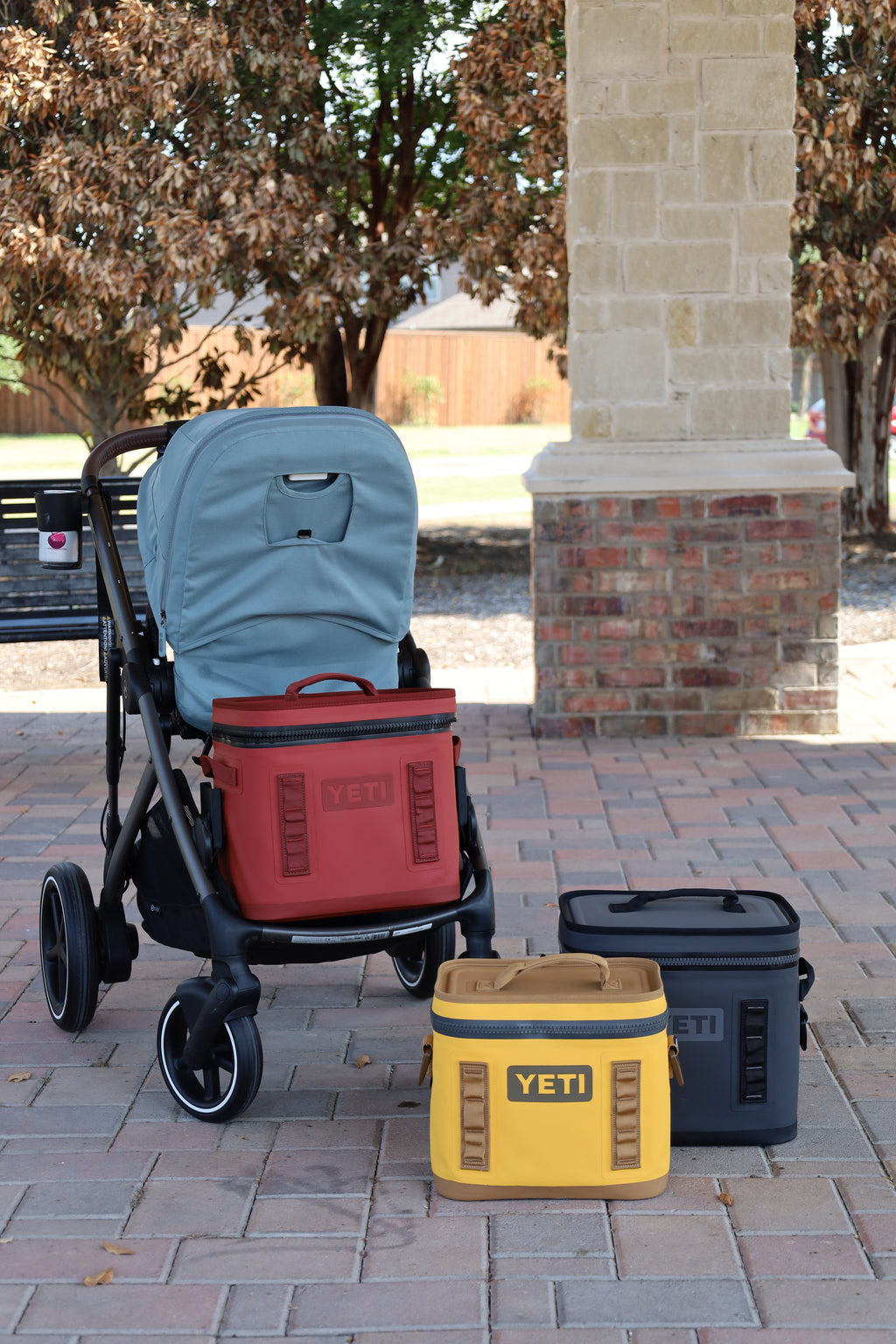 YETI Hopper Flip 12 riding in the lower slot of a CYBEX Gazelle S on the Stroller House cooler mount, next to a Hopper Flip 8 and a second Flip 12, the two sizes the mount is made for