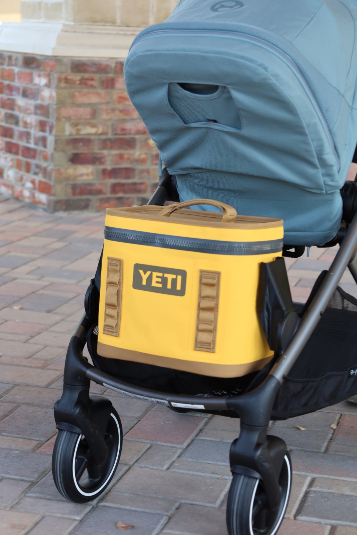 Yellow YETI Hopper Flip 8 held in the lower slot of a CYBEX Gazelle S by the Stroller House mount, sitting above the storage basket so the basket stays free for other gear