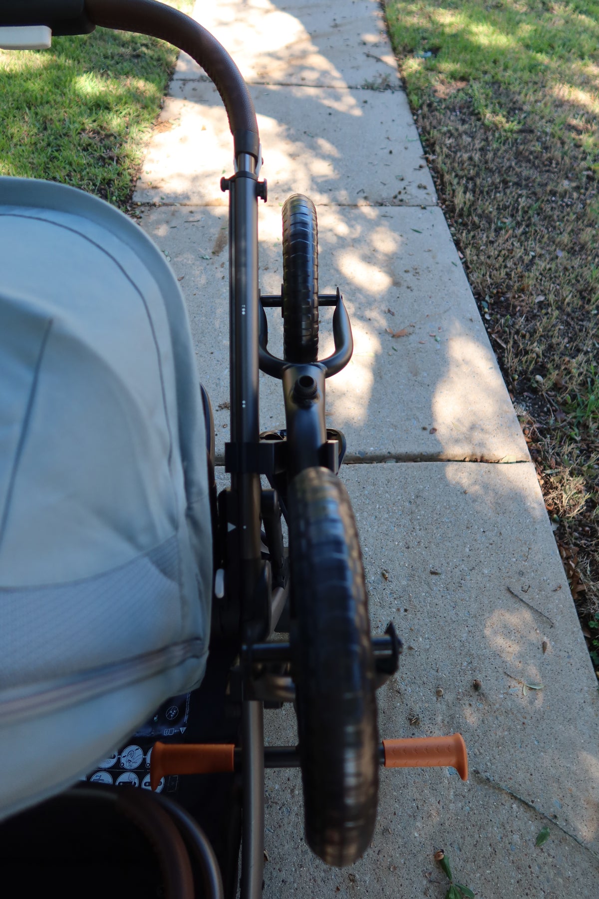 Looking forward along the CYBEX eGazelle S frame tube from the handle, showing the spacing between the two black holders and the balance bike resting in both cradles.