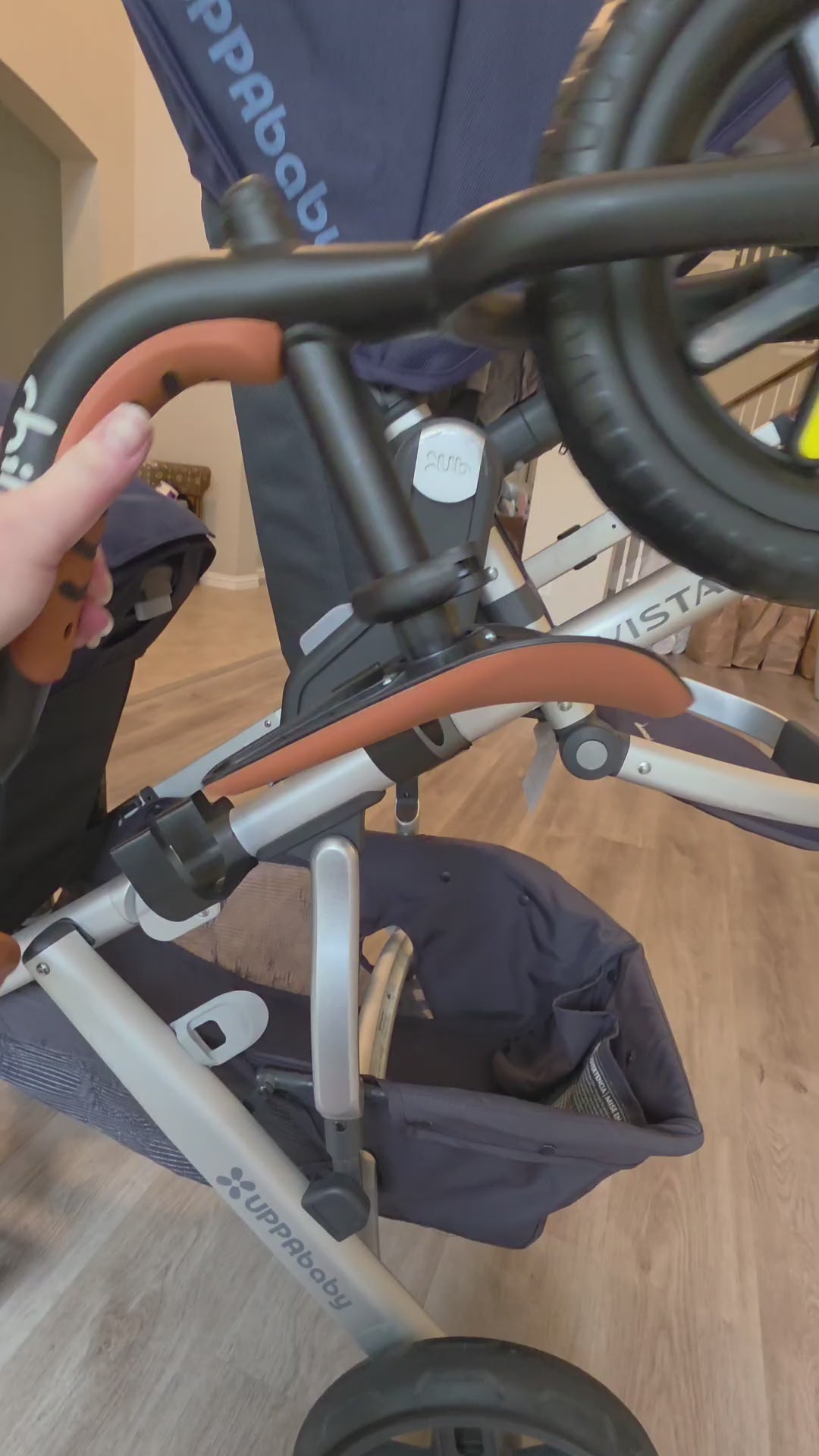 Walking around an UPPAbaby Vista with a balance bike loaded on the Stroller House holders, showing how it sits on the frame and clears the wheels.