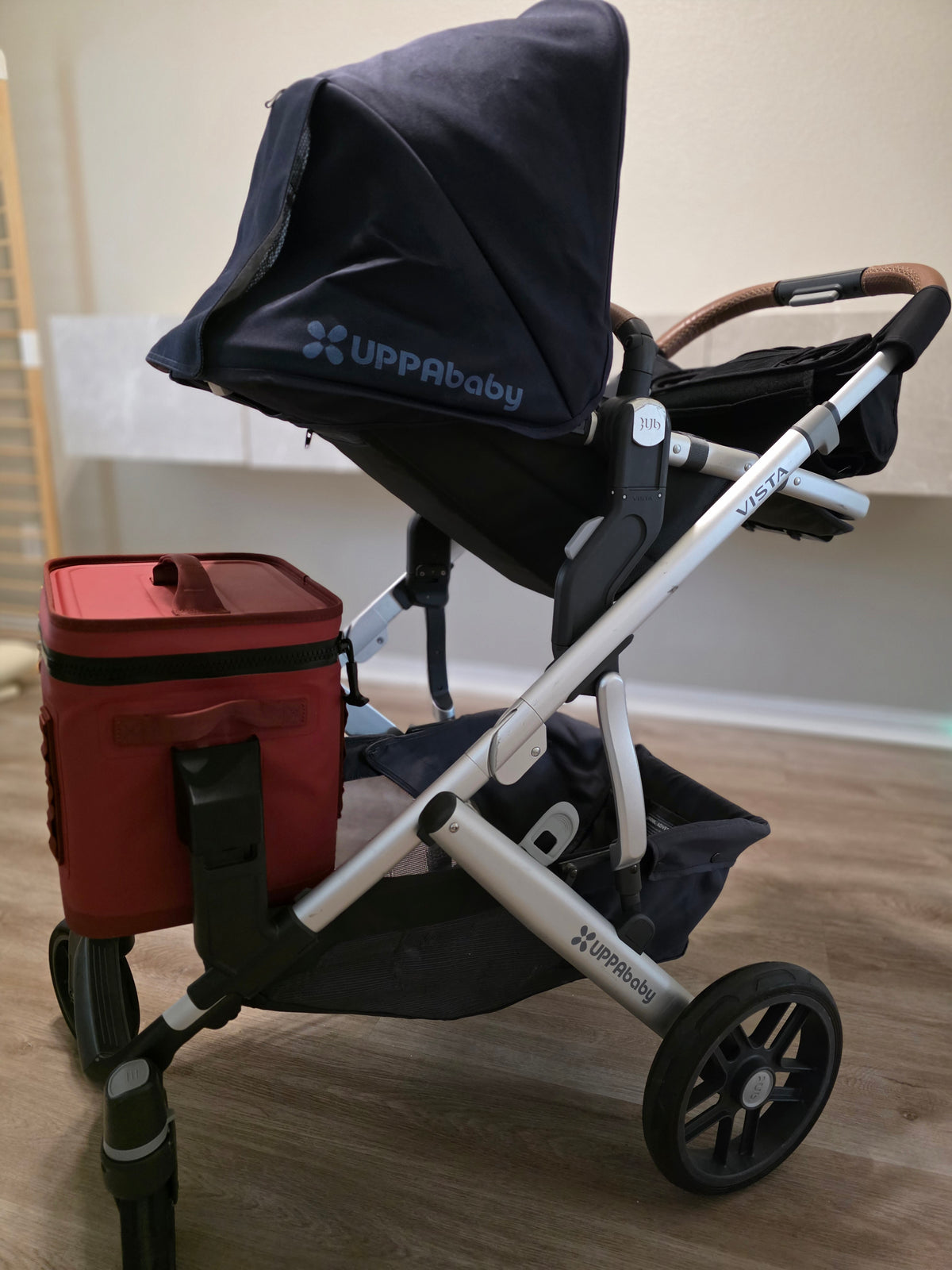 Side profile of an UPPAbaby Vista with a red YETI Hopper Flip 12 in the lower position and the storage basket still free underneath