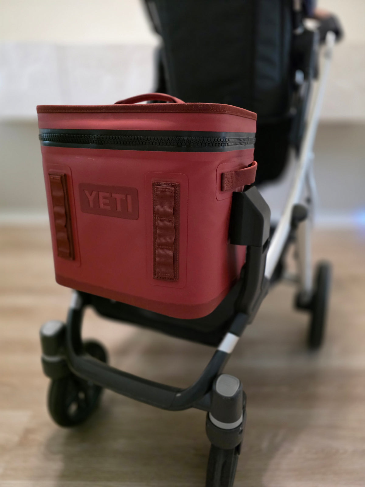Rear view of a red YETI Hopper Flip 12 sitting in the cooler mount on the lower adapter of an UPPAbaby Vista