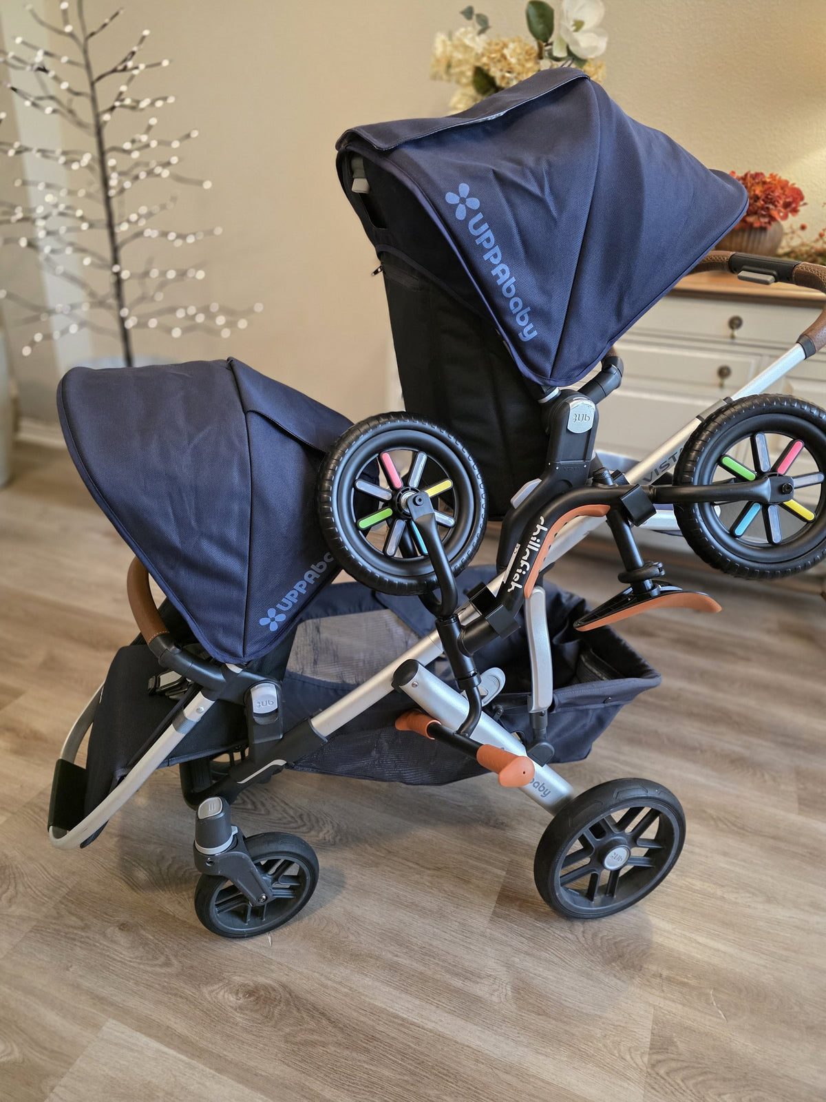 The same UPPAbaby Vista seen from above and in front, the balance bike riding on its holders low and inside the stroller's wheelbase.