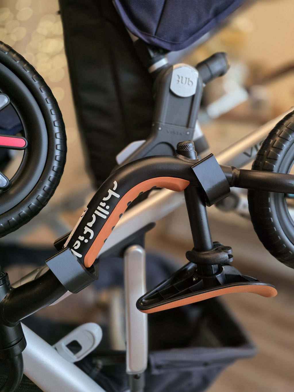 The balance bike's frame resting in the cradle of a Stroller House holder on the Vista frame tube, held by its own weight with no strap.